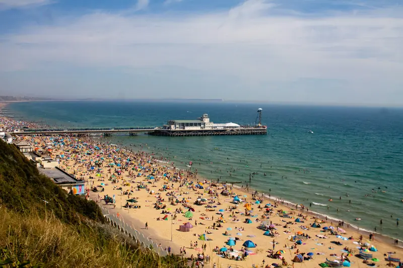 A busy Bournemouth beach and pier seen from the cliff top