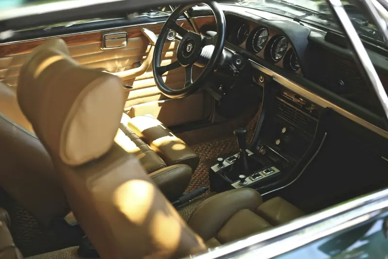 A classic car interior with clean leather seats and a polished wooden dashboard