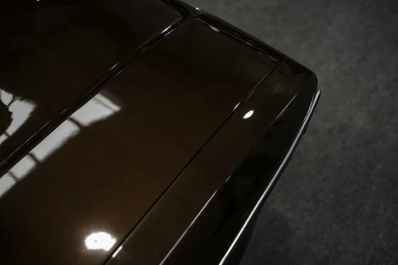 Deep, mirror-like reflections in a dark polished car panel