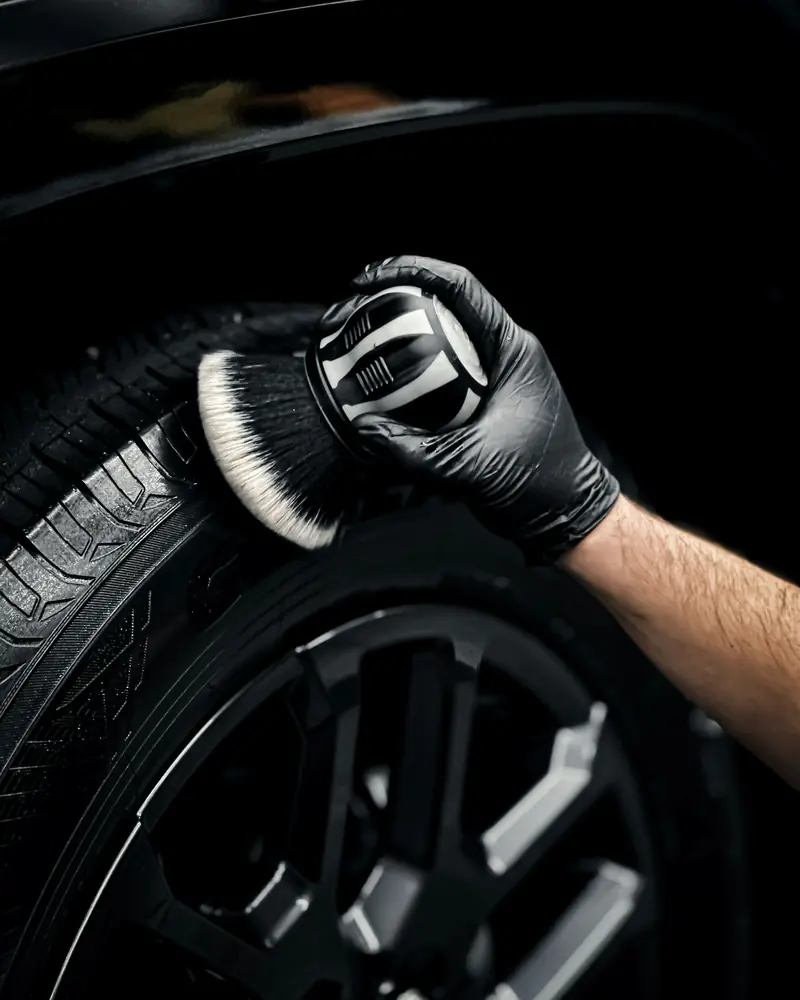 A detailing brush scrubbing an alloy wheel