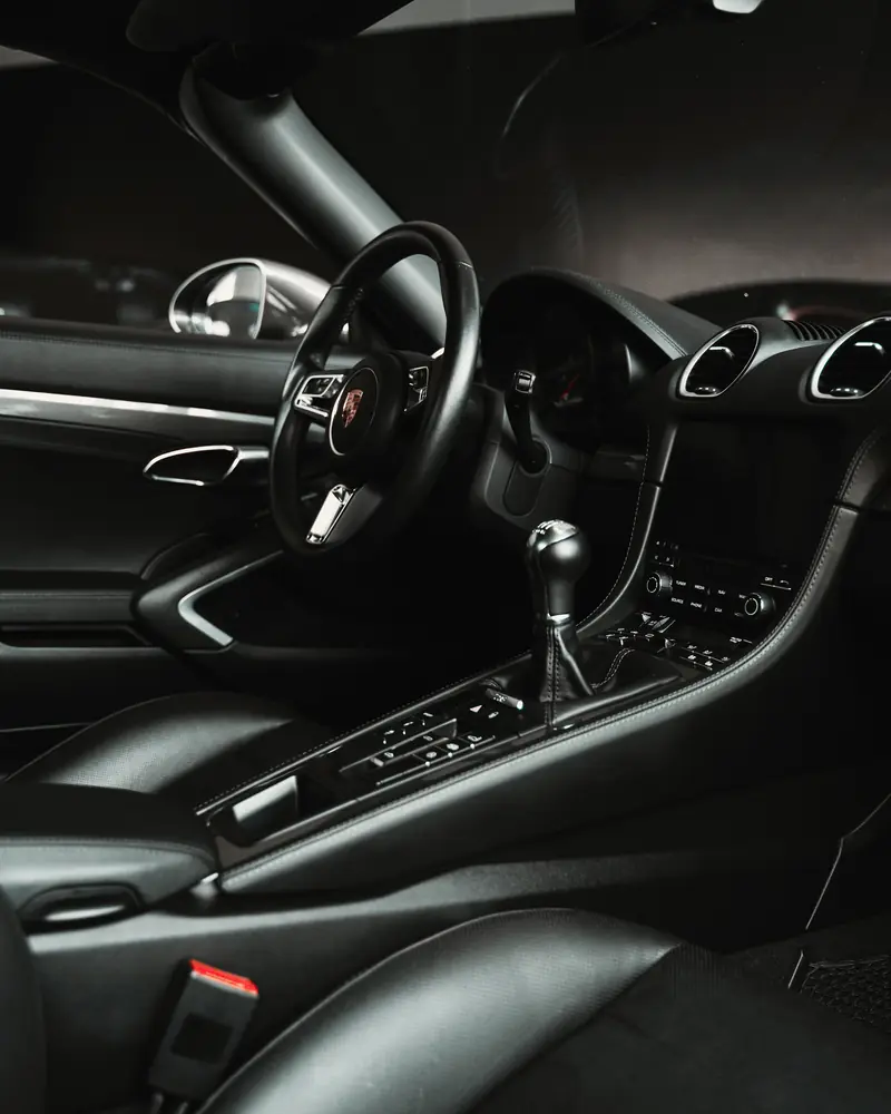 A clean dark leather interior with steering wheel and gear lever