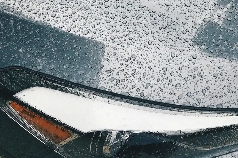 Raindrops sitting on a bonnet above a headlight